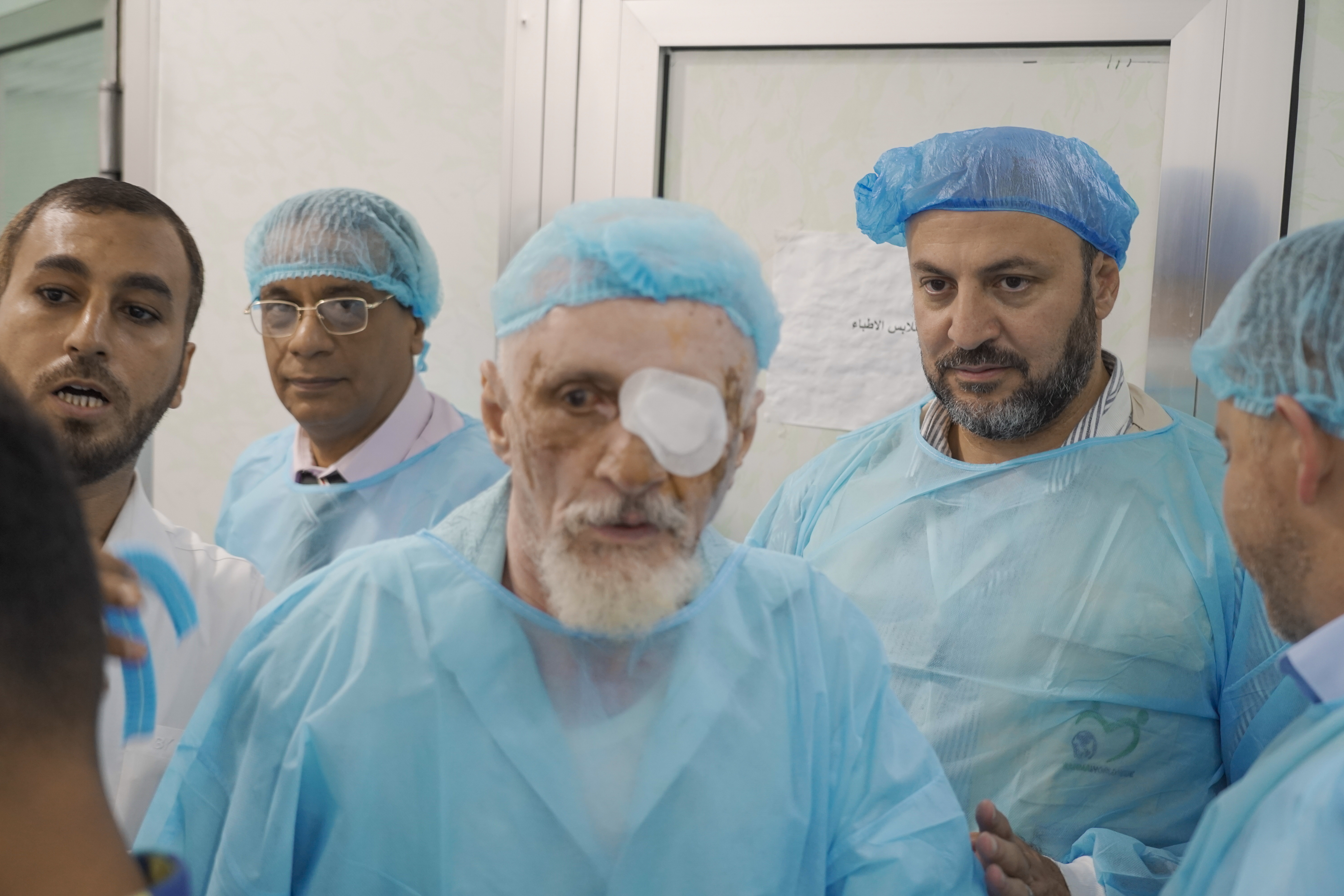 Medical team performing eye surgery on an elderly man